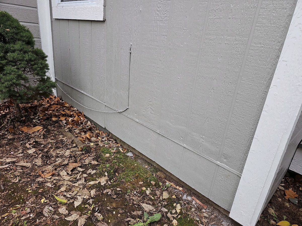 Engineered wood siding installed down to the soil with no clearance found during a home inspection in Bonner Springs, KS