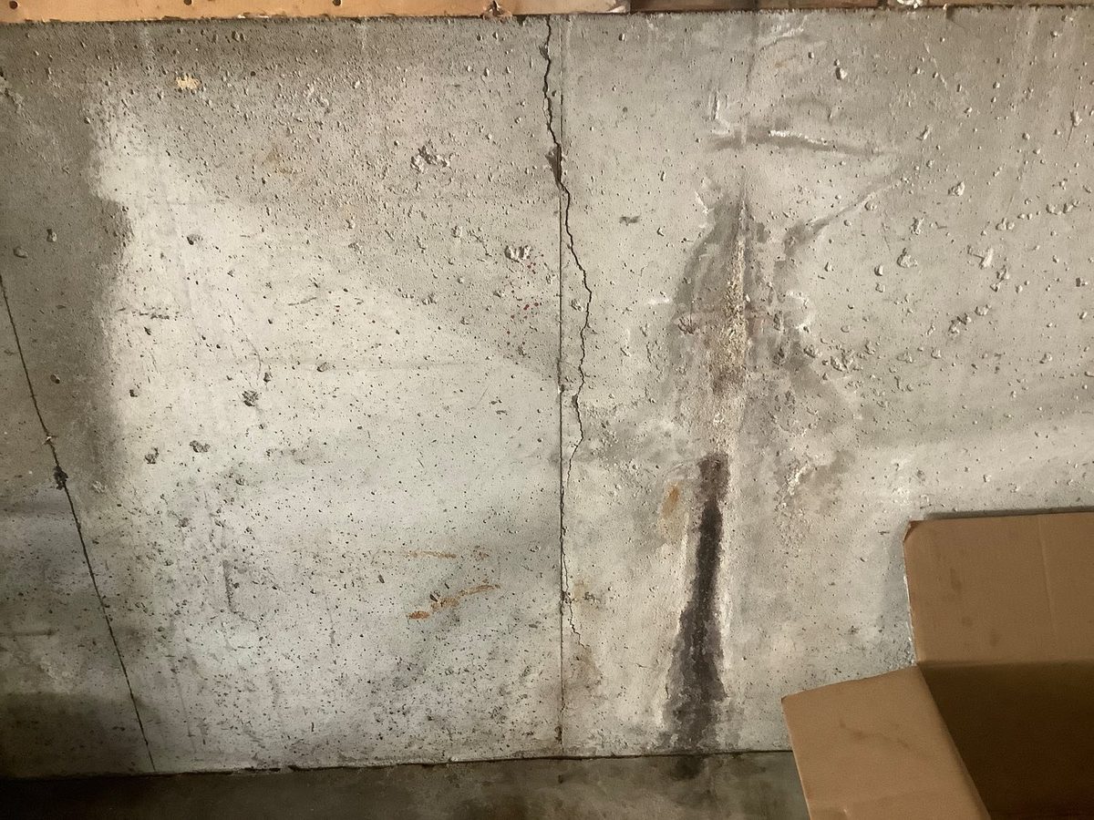 Vertical crack with a water trail on a poured concrete basement wall found during a home inspection in Gladstone, MO