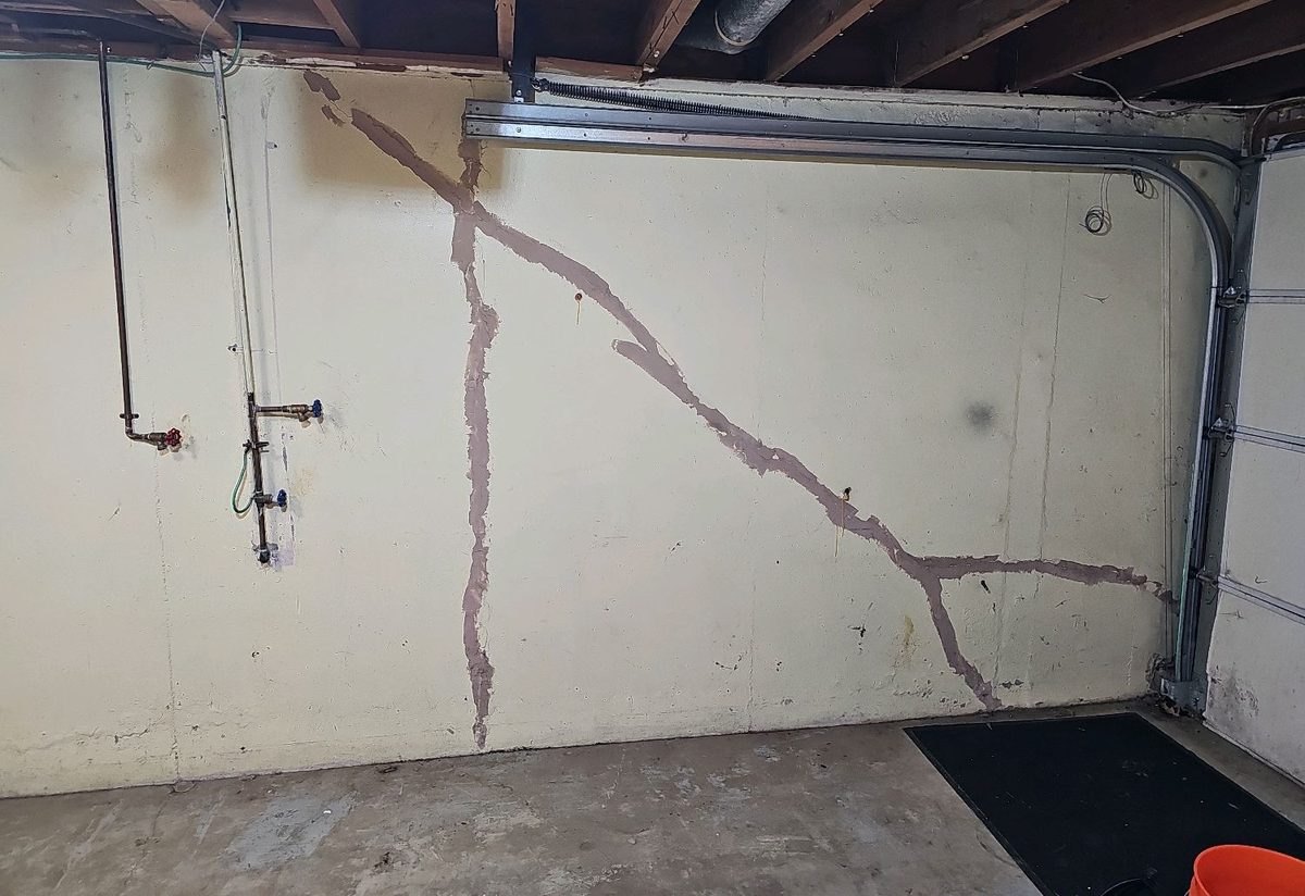 Patched diagonal and vertical cracks on a garage foundation wall found during a home inspection in Gladstone, MO
