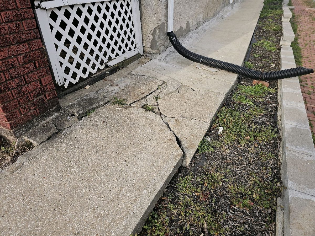 Broken and settled concrete walkway slab beside a foundation found during a home inspection in Kansas City, KS