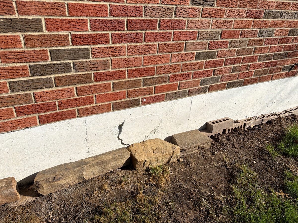 Cracked and spalled parging on an exterior foundation wall found during a home inspection in Kansas City, KS