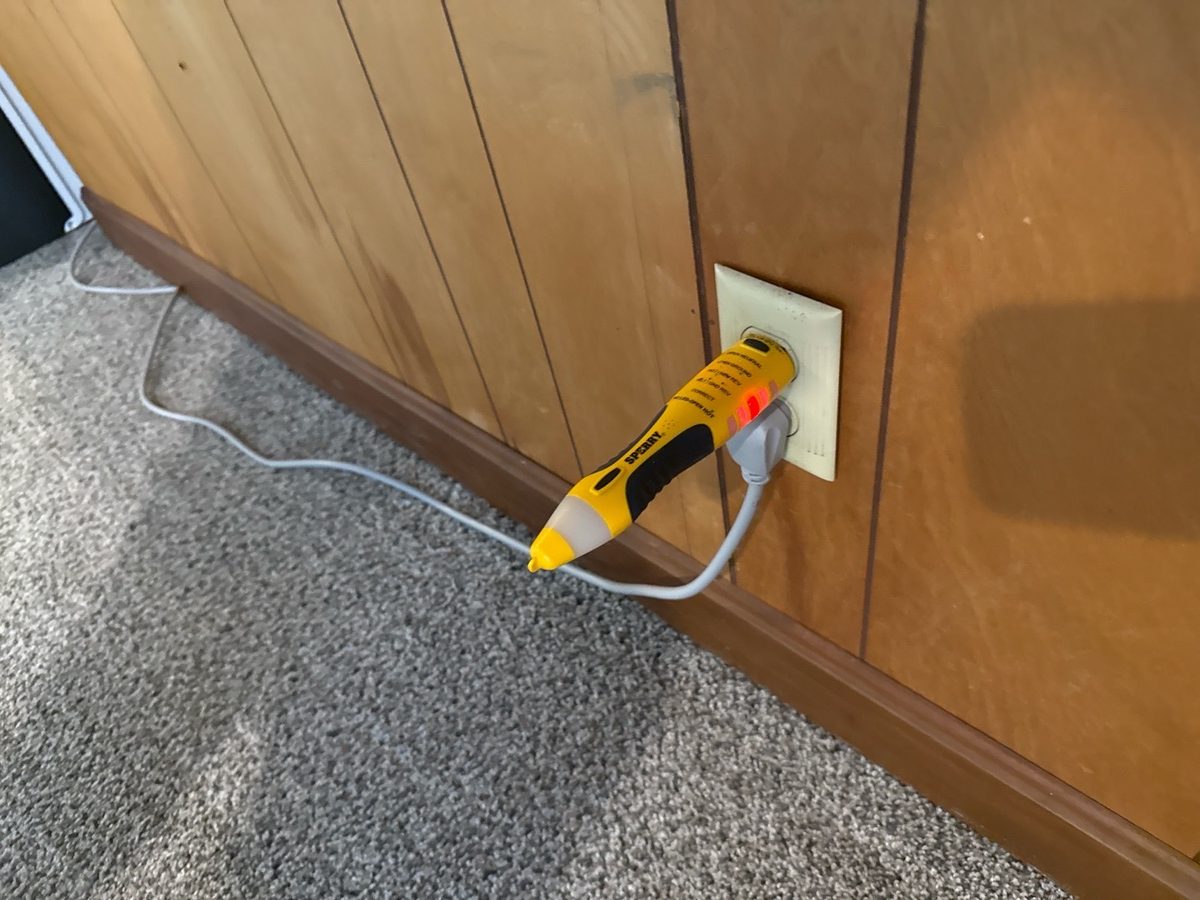 Plug-in outlet tester showing a red fault light at a wall outlet found during a home inspection in Kansas City, KS