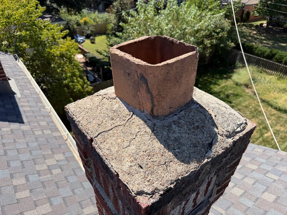 Cracked and patched concrete crown around a clay flue liner on a brick chimney, found during a home inspection in Kansas City, MO