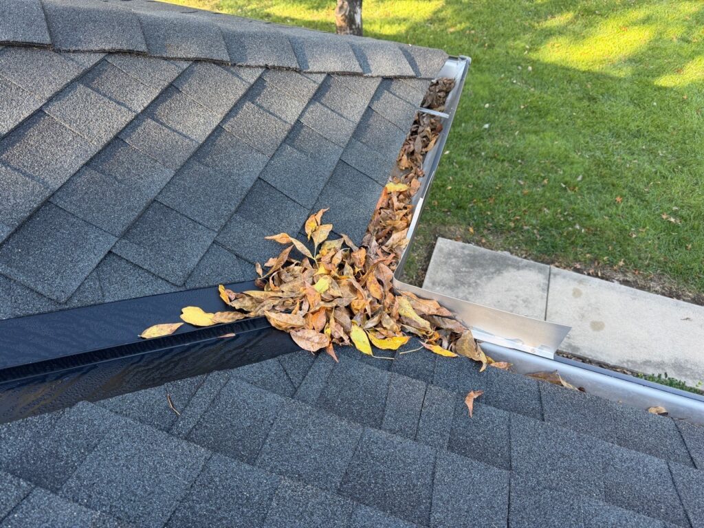 Fallen leaves piled in a gutter where two roof slopes meet, found during a home inspection in Kansas City, MO