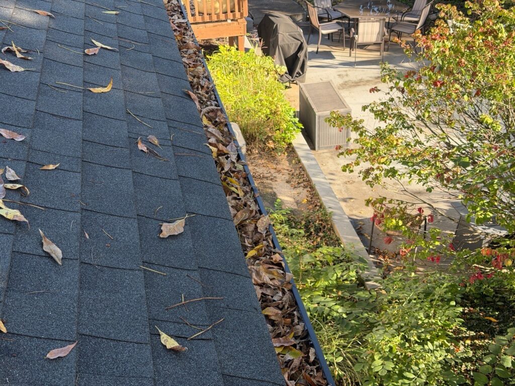 Gutter filled with leaves above a backyard patio, seen from the roof during a home inspection in Kansas City, MO