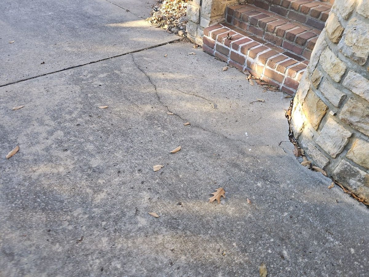 Cracked concrete walkway beside brick and stone front steps found during a home inspection in Leawood, KS