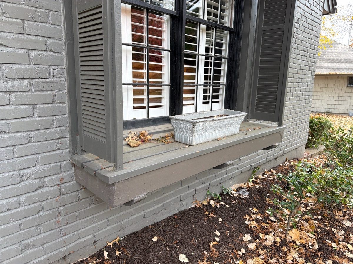 Weathered, decaying wood window box and trim on a painted brick home found during a home inspection in Leawood, KS