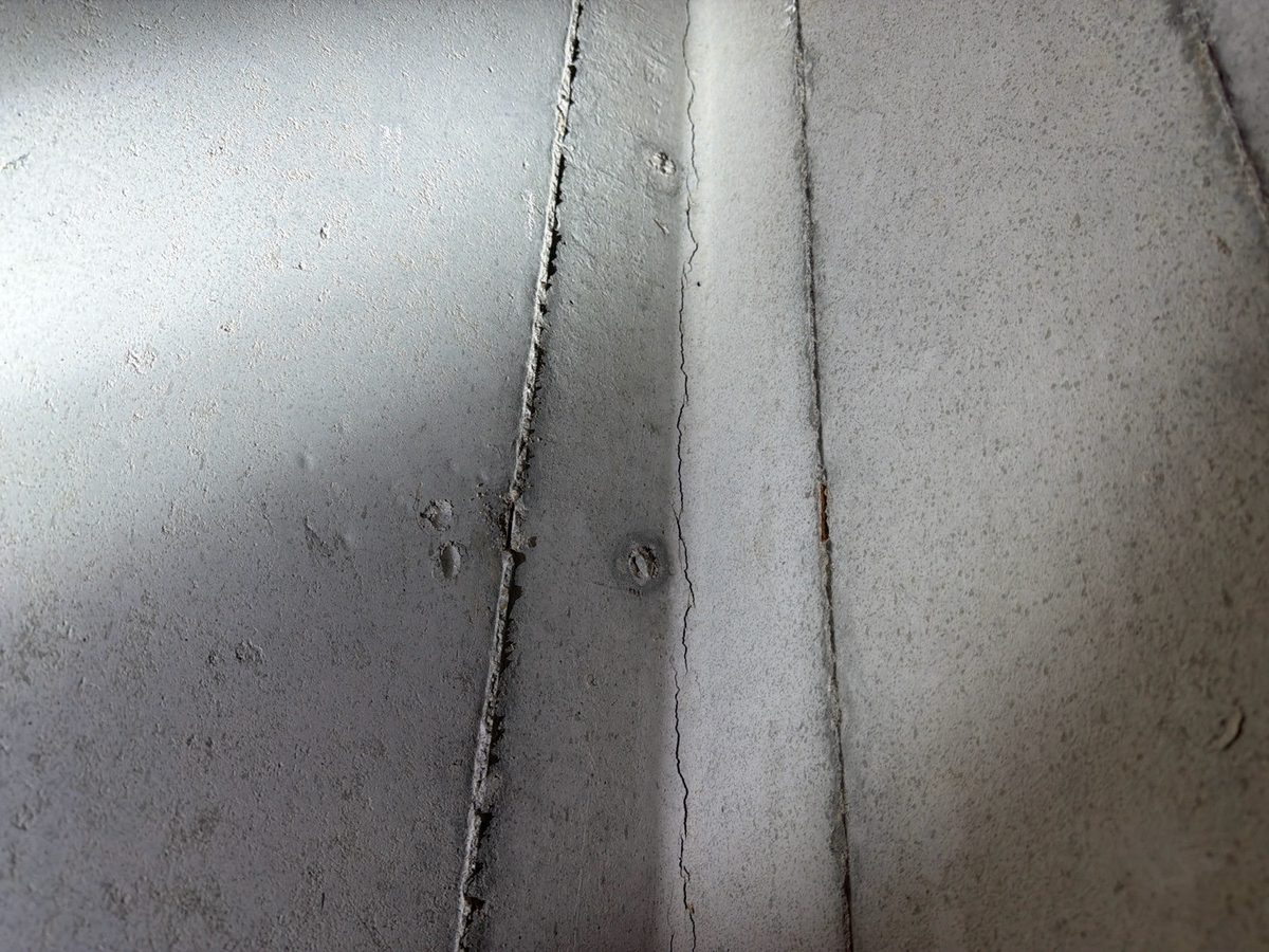 Hairline crack running down a poured concrete basement wall beside a form seam found during a home inspection in Lenexa, KS
