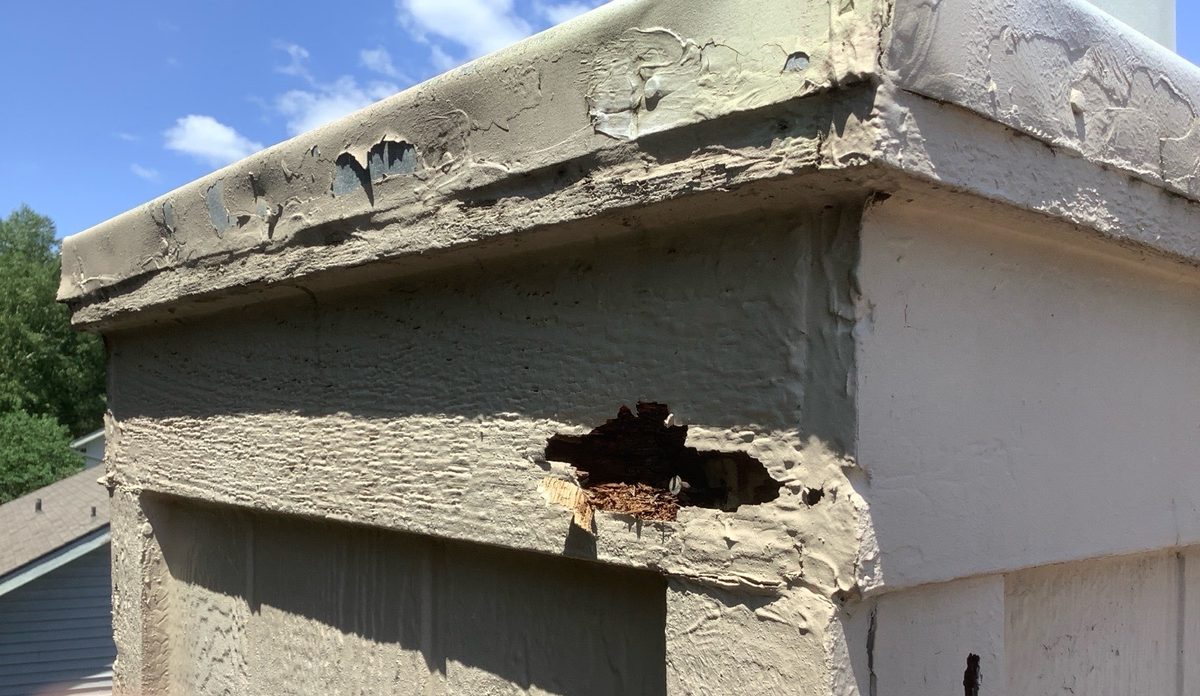 Rotted wood trim below a weathered cap on an exterior chase found during a home inspection in Liberty, MO