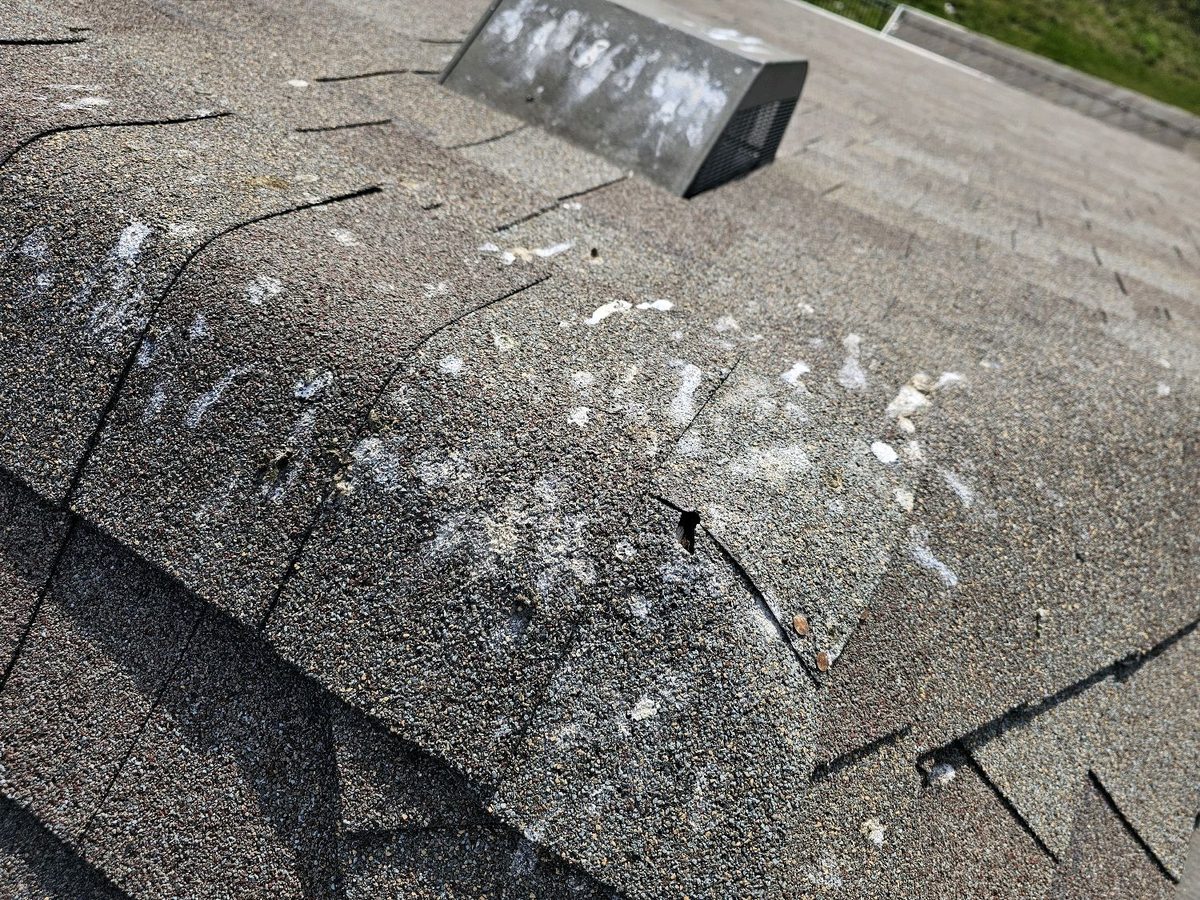 Split and punctured ridge cap shingles on an asphalt roof found during a home inspection in Kearney, MO