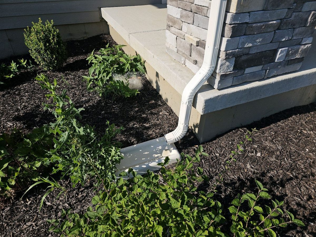 Short downspout discharge on a splash block next to the foundation found during a home inspection in Olathe, KS