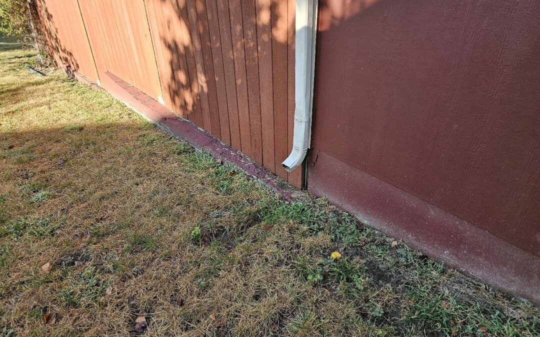 Downspout ending at the base of a house's siding with no extension, found during a home inspection in Olathe, KS