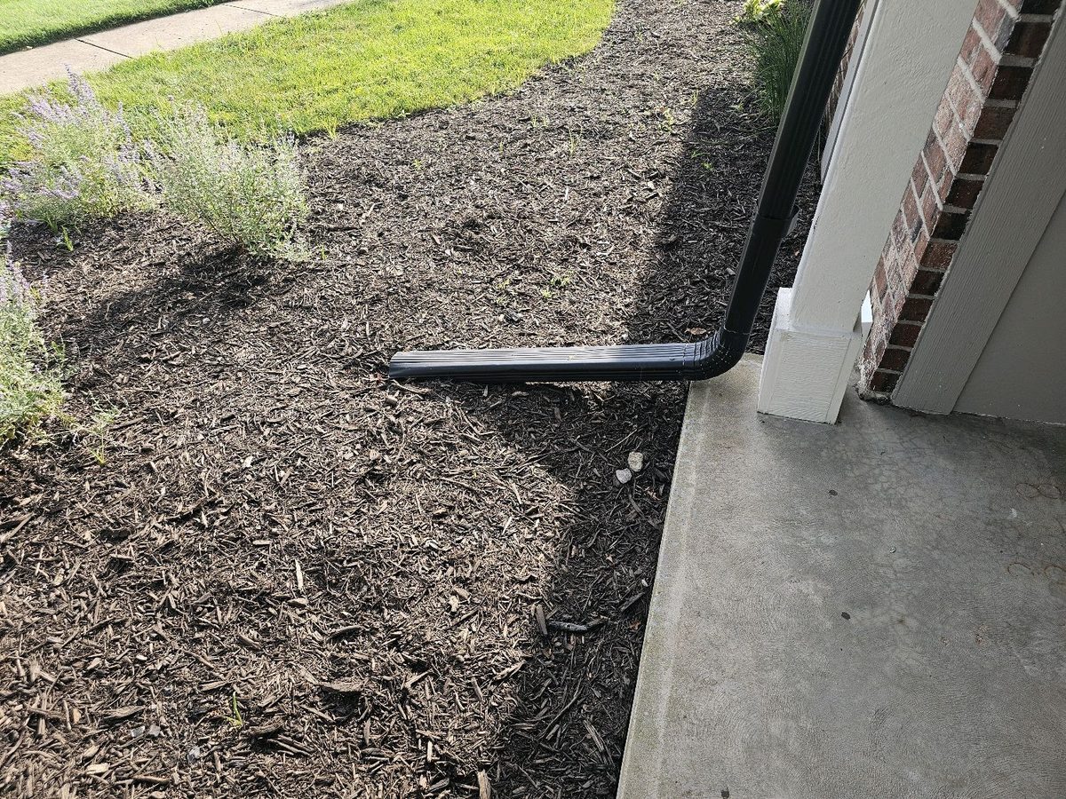 Short downspout discharge on a mulch bed against the foundation found during a home inspection in Overland Park, KS