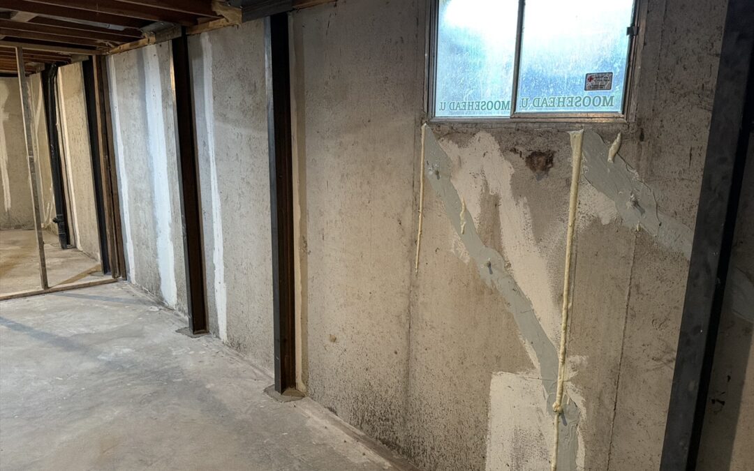 Row of steel wall braces and injected, sealed diagonal cracks on a poured concrete basement wall found during a home inspection in Overland Park, KS
