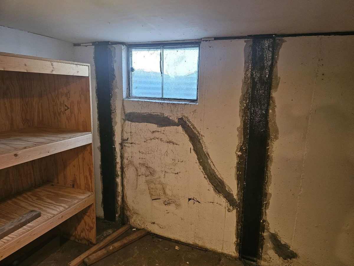 Reinforcement straps over a sealed diagonal crack on a basement foundation wall found during a home inspection in Overland Park, KS