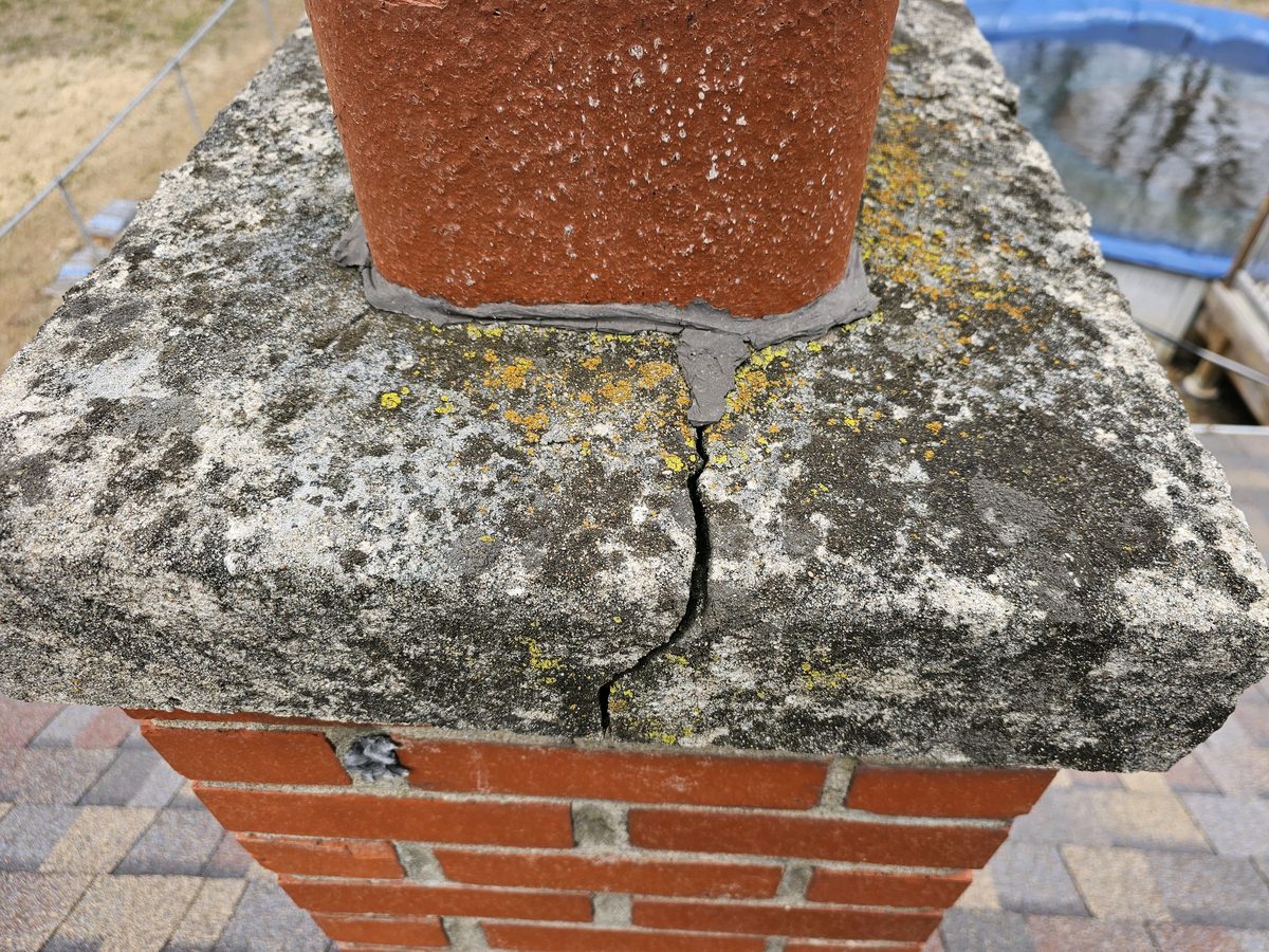 Cracked mortar crown on a brick chimney beside the clay flue liner found during a home inspection in Raytown, MO