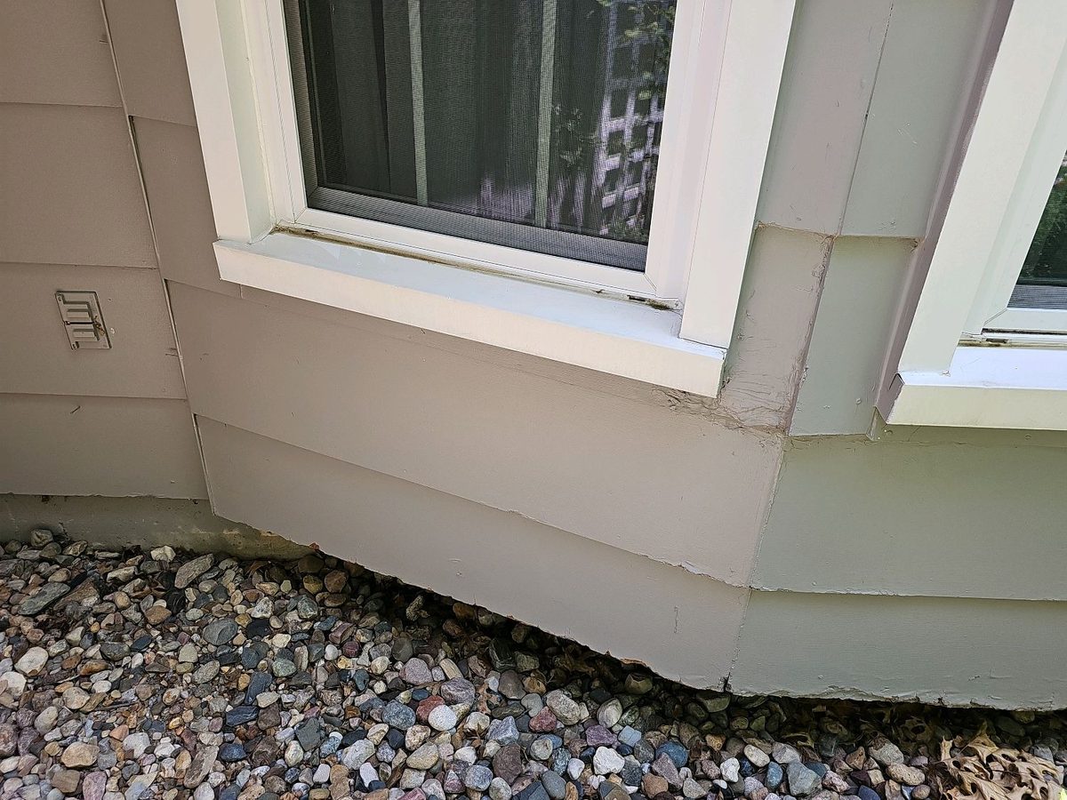 Swelling and decay on the bottom edge of engineered wood siding below a bay window found during a home inspection in Shawnee, KS